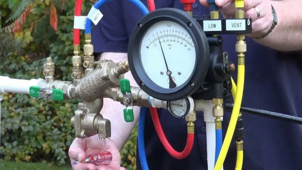 Technician testing a backflow prevention device with a pressure gauge