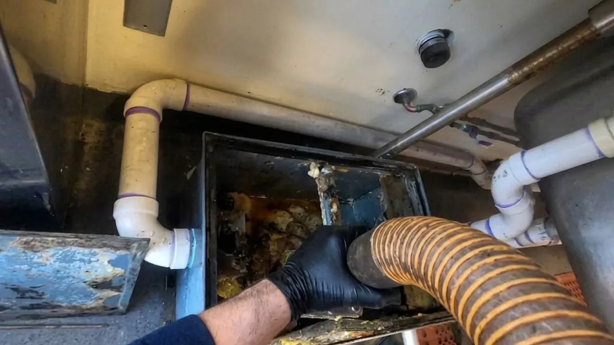 Plumber servicing a commercial grease trap and drain line