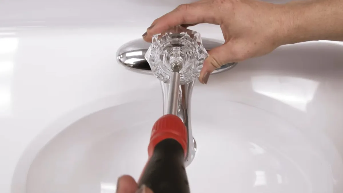 Plumber repairing a bathroom sink faucet handle