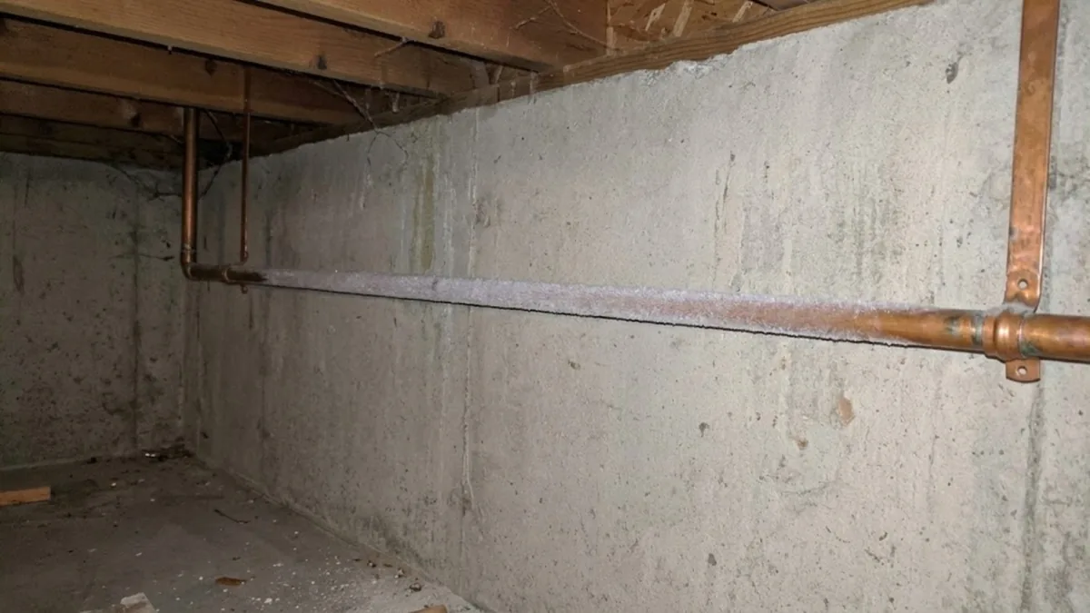 Frost-covered copper pipe in an unheated crawlspace