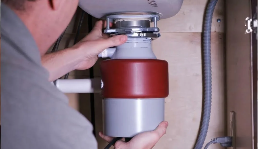 Plumber installing a garbage disposal unit under a kitchen sink