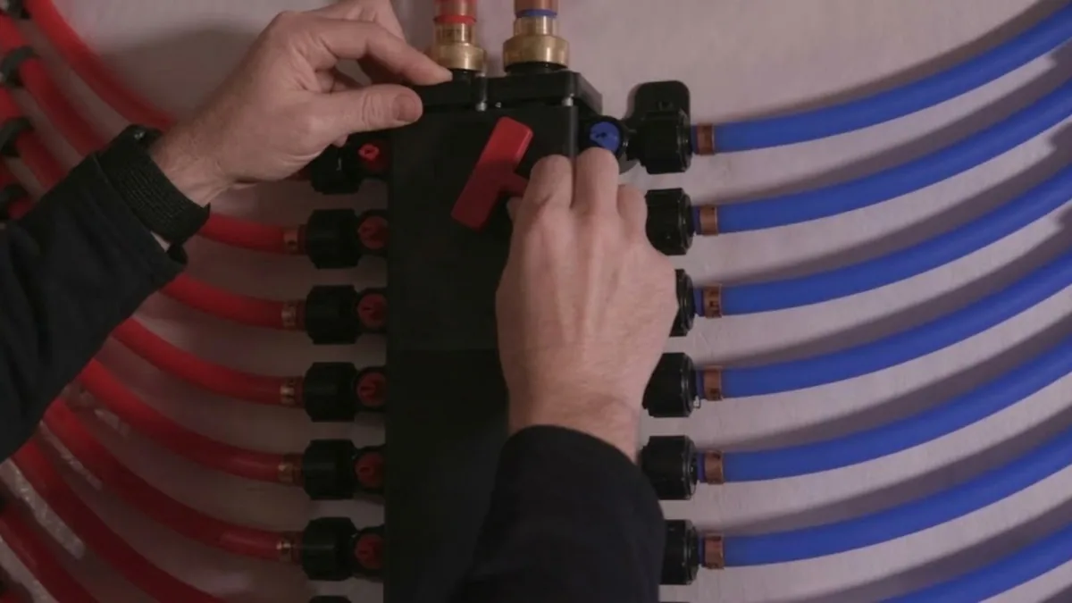 Plumber connecting a PEX pipe manifold during a whole-home repipe