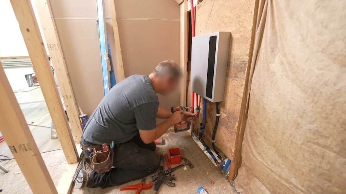 Technician installing a wall-mounted tankless water heater unit