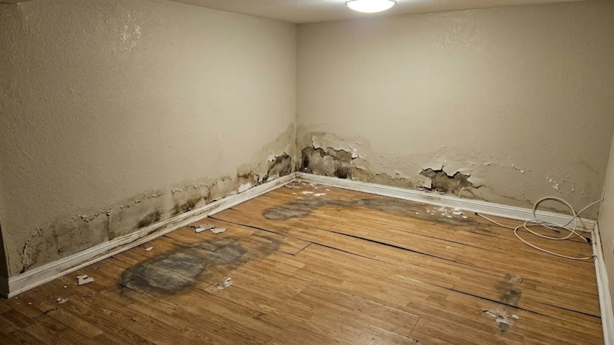 Water-damaged room with peeling drywall and warped flooring before restoration