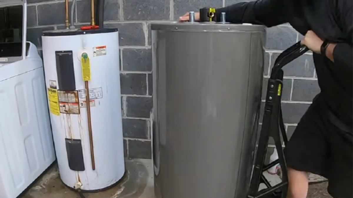 New water heater being wheeled in next to an old unit for replacement